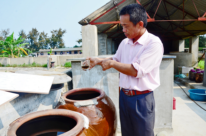 Anh Nguyễn Hữu Lương, chủ cơ sở sản xuất giới thiệu sản phẩm mắm cá cơm chứa trong ang.