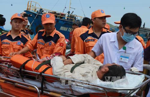 Lực lượng cứu nạn cùng y, bác sỹ hỗ trợ đưa ngư dân đi cấp cứu. Ảnh: Nguyên Lý/TTXVN