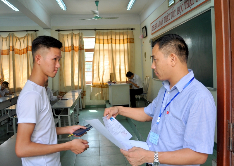 Cán bộ coi thi tại điểm thi THPT Hoàng Quốc Việt (TX Đông Triều)  kiểm tra thẻ dự thi của thí sinh trước khi bước vào phòng thi