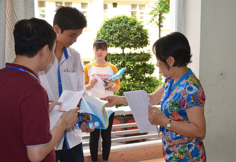 Cán bộ coi thi tại điểm THPT Hòn Gai (TP Hạ Long)  kiểm tra thẻ dự thi của thí sinh trước khi bước vào phòng thi