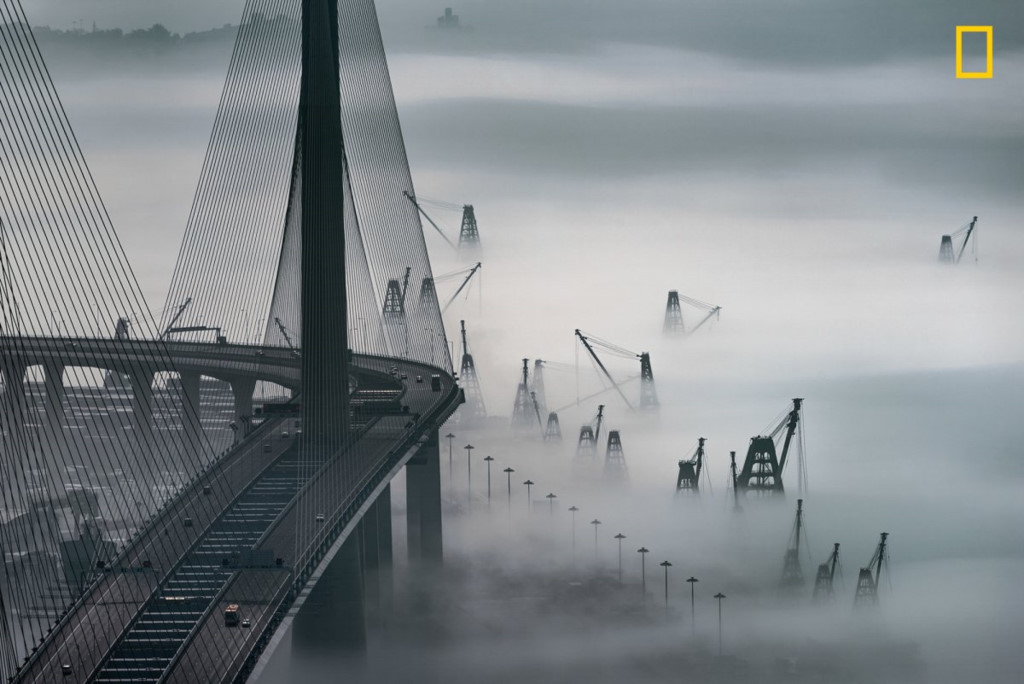 Hong Kong (Trung Quốc) chìm trong sương mù khi nhìn từ cảng Kwai Tsing, chỉ có cây cầu Stonecutters và những chiếc cần cẩu xây dựng còn hiện rõ.