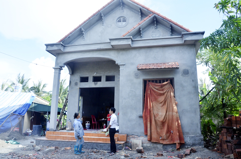 Vợ thương binh Lê Văn Hùng, khu phố 11, phường Hà An, TX Quảng Yên bên ngôi nhà được xây mới từ chính sách hỗ trợ nhà ở cho NCC.