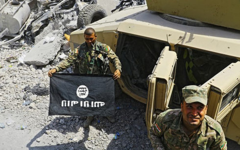Quân nhân Iraq cầm lá cờ đen IS giữa đống đổ nát tại Thành Cổ Mosul. Ảnh: UPI.