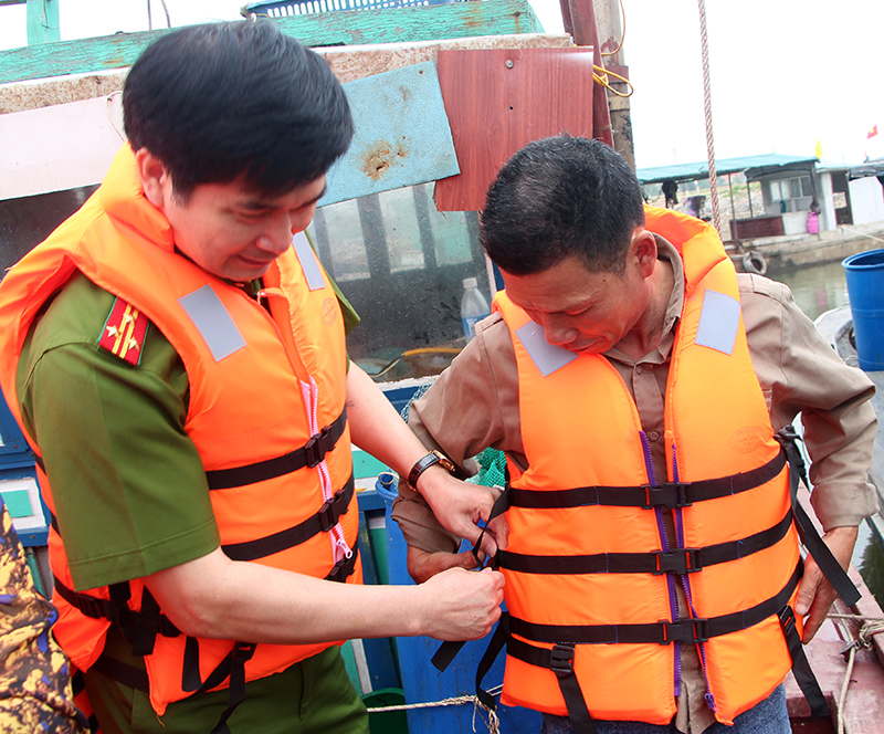Lãnh đạo Công an tỉnh tặng áo phao và hướng dẫn ngư dân TX Quảng Yên sử dụng áo phao khi tham gia giao thông đường thuỷ.