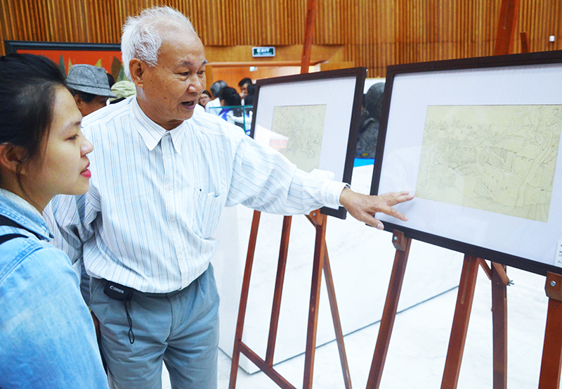 Họa sĩ Phạm Phi Châu bên một số bức tranh của mình được trưng bày tại Bảo tàng Quảng Ninh.