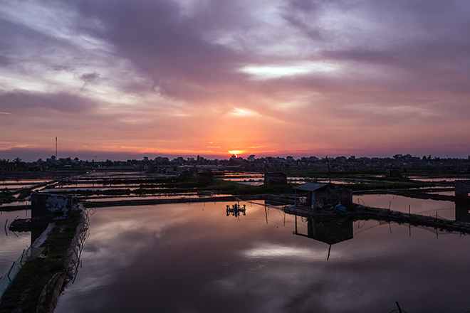 Khi mặt trời dần lặn sau rặng núi, biển Đồng Châu nhuộm một màu tím biếc hoang hoải với những nhà sàn gỗ ven biển như một điểm nhấn tô điểm cho khung cảnh nơi đây.
