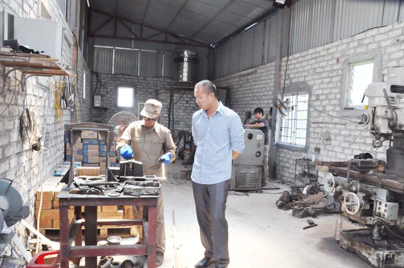 Anh Nguyễn Trường Quân (bên phải), Giám đốc Công ty TNHH 2TV Trường Quân, giám sát công nhân thi công sản phẩm tại nhà xưởng của Công ty. 