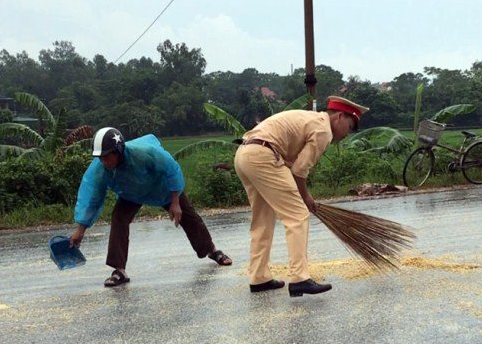 Lực lượng công an và người dân TX Đông Triều hỗ trợ lái xe thu gom lại số ngô hạt bị đổ ra đường