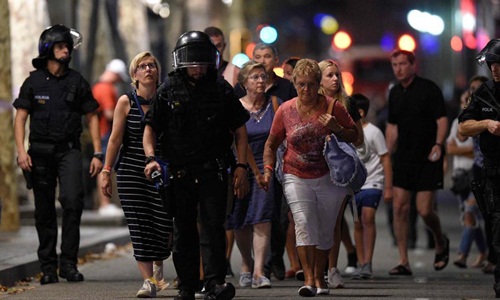 Cảnh sát hộ tống người dân rời khỏi hiện trường vụ lao xe ở Las Ramblas, trung tâm thành phố Barcelona, Tây Ban Nha. Ảnh: AFP.