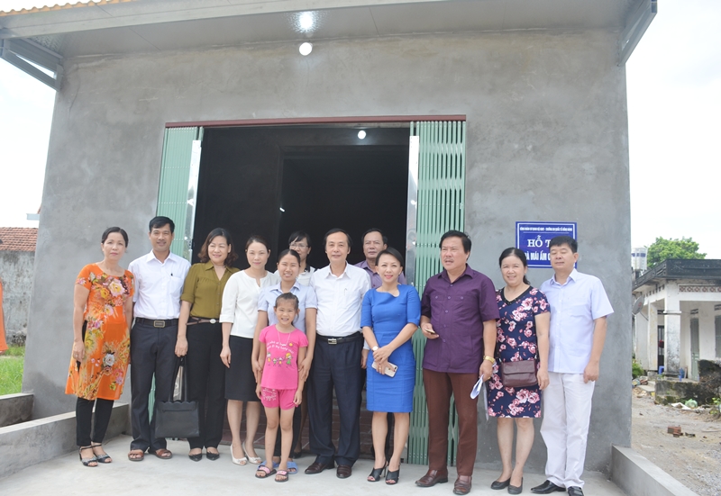 Các thành viên đoàn công tác chụp ảnh lưu niệm bên ngôi nhà mới của cô giáo Khâu Thị Thu Hòa, Trường Tiểu học Thống Nhất