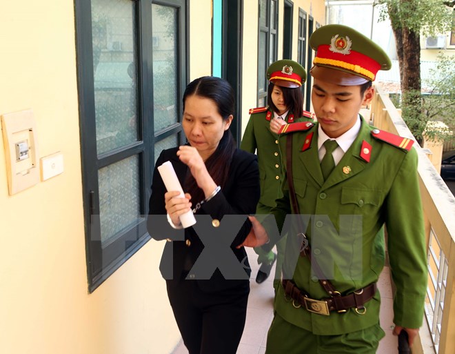 Lực lượng chức năng dẫn giải bị cáo Nguyễn Minh Thu, nguyên Tổng Giám đốc Ngân hàng Oceanbank đến Phiên tòa xét xử. (Ảnh: Phạm Kiên/TTXVN)