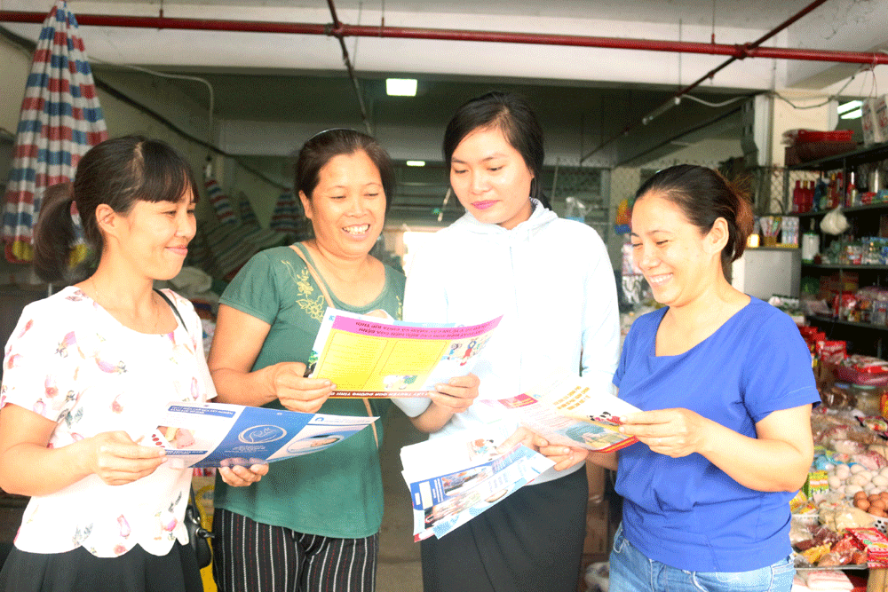 Chị Trần Thị Thu Huyền, cán bộ Trung tâm DS-KHHGĐ huyện Bình Liêu phát tờ rơi cho chị em tiểu thương tại Chợ Trung tâm Bình Liêu vận động sinh đẻ có kế hoạch