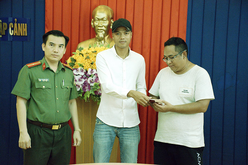 Đại diện Phòng Quản lý xuất nhập cảnh và anh Thái trao trả cuốn hộ chiếu cho ông A. ZENGMEI.