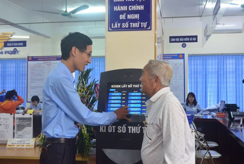 Cán bộ Trung tâm HCC TP Uông Bí hướng dẫn người dân lấy số thứ tự để giải quyết thủ tục hành chính.