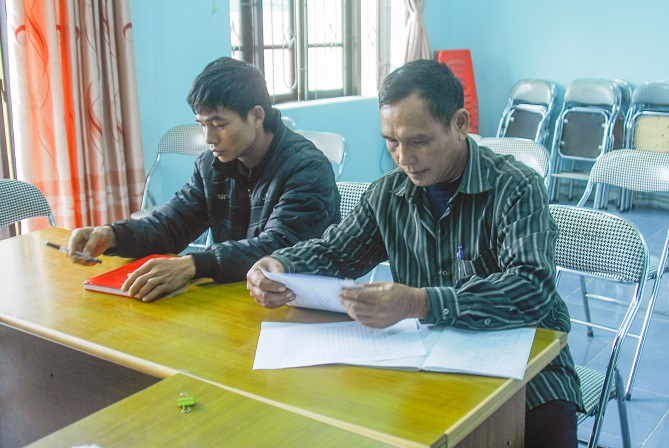 Ông Lô Tiến Hải (bên phải), Bí thư chi bộ kiêm trưởng thôn Bản Ngày 1, xã Vô Ngại, huyện Bình Liêu, rà soát danh sách hộ nghèo của thôn