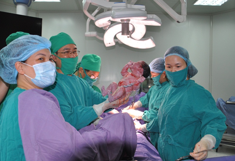 Các bác sỹ Bệnh viện Sản Nhi Quảng Ninh đón em bé đầu tiên ra đời bằng thụ tinh nhân tạo. Ảnh: Hoàng Quý