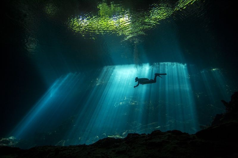 Ánh sáng mặt trời chiếu vào nước trong khi một thợ lặn bơi trong một hang động đá vôi ở Mexico, tạo nên vẻ đẹp huyền bí. (Nguồn: NatGeo)
