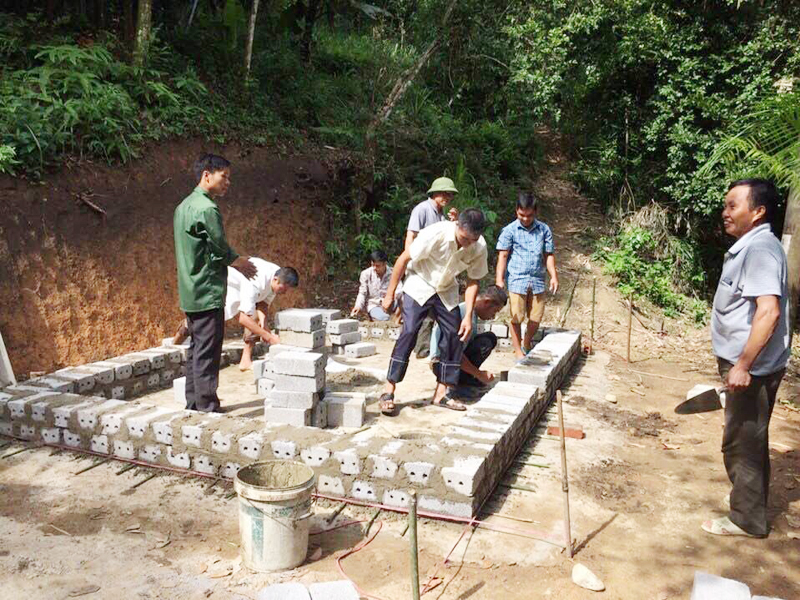 Cán bộ xã Đồng Tâm hỗ trợ, hướng dẫn gia đình bà Lý Thị Hải (thôn Phiêng Chiểng) làm chuồng trâu thoát nước tự động từ nguồn vốn Chương trình 135