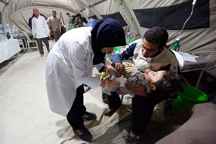 Nhân viên y tế chăm sóc một em bé bị thương, tại một bệnh viện tạm thời. Ảnh: EPA.