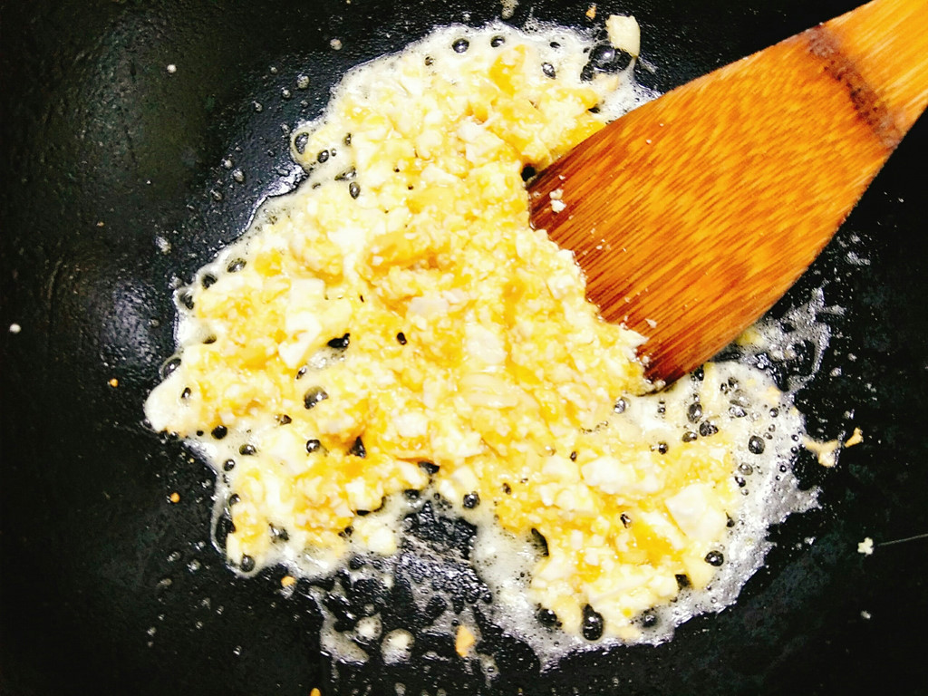 Đặt chảo lên bếp cùng với 2 thìa dầu ăn, khi dầu nóng bạn cho tỏi băm vào phi cho thơm sau đó cho trứng muối vào xào cho trứng nổi bọt dậy mùi thơm.