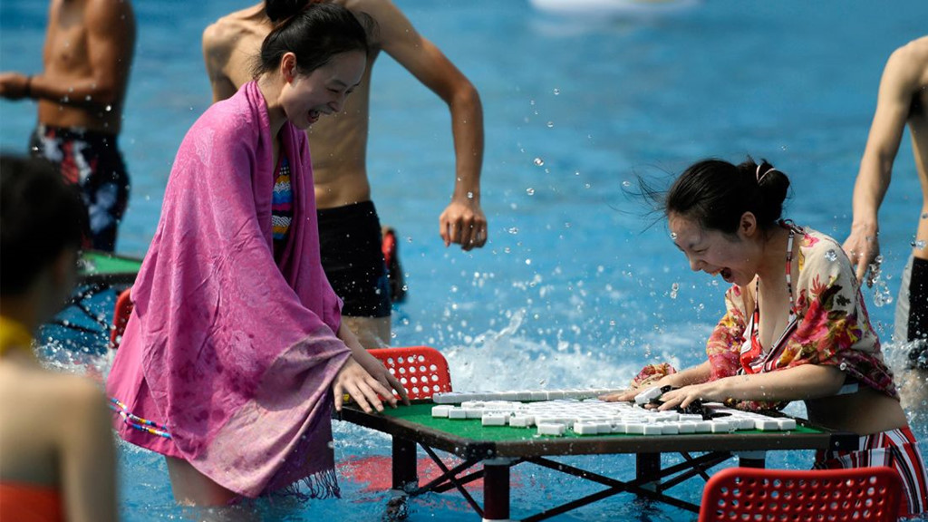 Trùng Khánh nổi tiếng là một trong những thành phố có thời tiết mùa hè nóng nhất Trung Quốc. Người dân ở đây chống lại cái nóng bằng cách chuyển bàn mạt chược ra các bể bơi. Ảnh: STR/AFP/Getty Images.