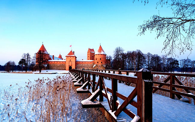 Lâu đài Trakai, Lithuania: Nằm cách mười bảy dặm về phía tây của Vilnius, lâu đài Traikai càng trở nên lộng lẫy hơn vào những tháng mùa đông, khi hồ nước xung quanh bị đóng băng và các chóp nhọn lợp ngói đỏ của tòa lâu đài bị tuyết phủ lốn đốm càng trở nên nổi bật trong sắc trắng bao phủ khắp mọi nơi.