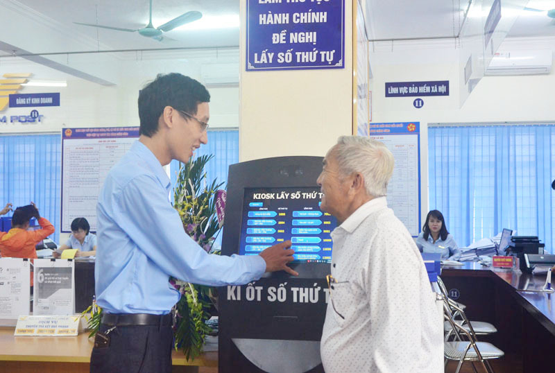 Cán bộ Trung tâm HCC TP Uông Bí hướng dẫn người dân lấy số thứ tự tại ki ốt để giải quyết thủ tục hành chính. 