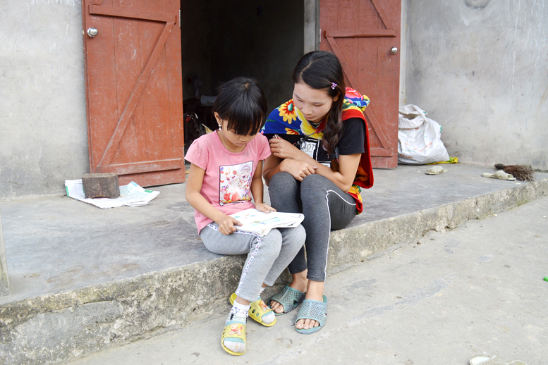 Chị Tằng Thị Nguyệt, khu Nhì Cáu, bản Lồ Má Coọc xã Quảng Sơn, huyện Hải Hà tranh thủ trời còn sáng để dạy chữ cho con. 