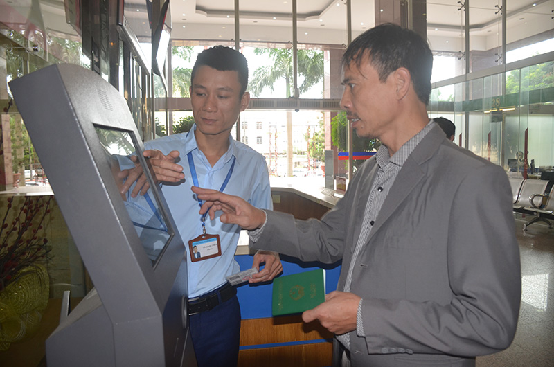 Cán bộ Trung tâm hành chính công tỉnh hướng dẫn người dân lấy số thứ tự (Ảnh: Nguyễn Chiến)