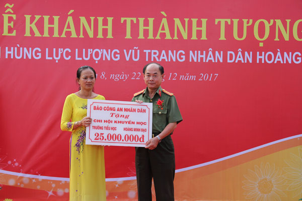 Đại tá Trần Kim Thẩm trao quà tặng của Báo CAND cho các em học sinh có hoàn cảnh khó khăn.