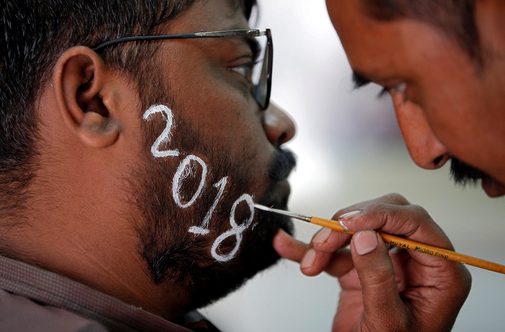 Một thợ cắt tóc đang vẽ số 2018 lên râu của một người đàn ông để đón năm mới tại Ấn Độ. (Ảnh: Sky News)