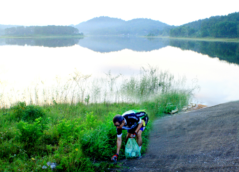 Tranh thủ lúc giải lao, anh Vũ Viết Nhuận nhặt rác thải xung quanh khu vực hồ Yên Trung mang về nơi tập kết rác thải