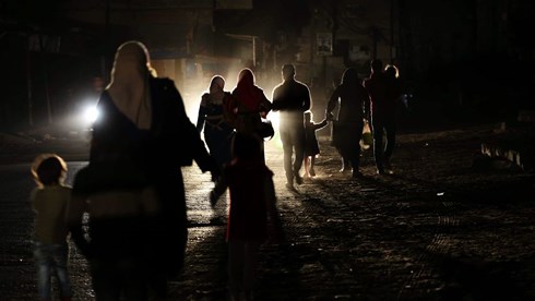 Người dân Palestine đi lại trên phố trong một buổi tối bị cắt điện ở Gaza. Ảnh: NurPhoto.