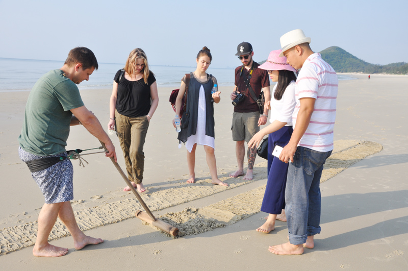 Khách du lịch quốc tế trải nghiệm cào ngao tại bãi biển Sơn Hào (Vân Đồn)