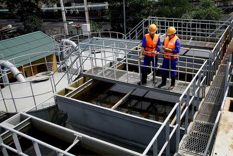 Công nhân Xí nghiệp Xử lý nước Cẩm Phả kiểm tra, vận hành trạm xử lý nước thải mỏ Giáp Khẩu. (Ảnh: Dương Phượng Đại). 