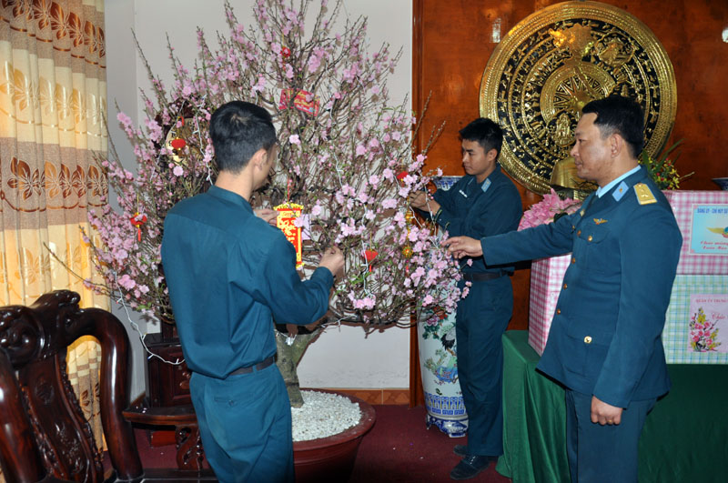 Trung tá Phí Việt Thành (đầu tiên, bên phải) cùng đồng đội trang trí cành đào đón năm mới