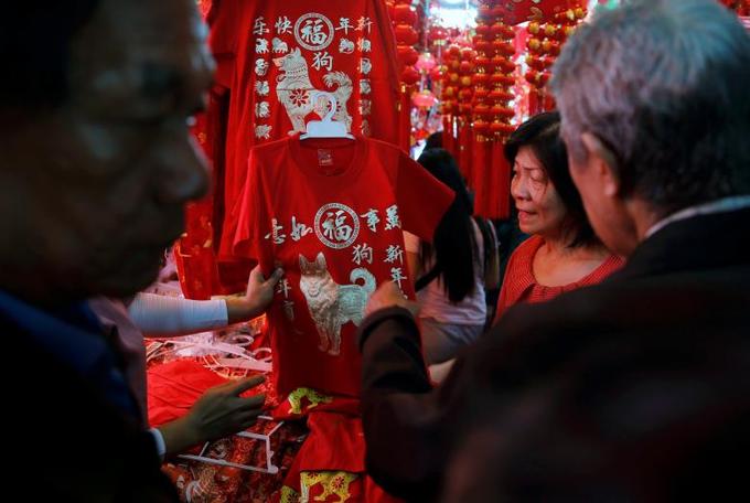 Một người đang hỏi mua chiếc áo phông in hình linh vật của năm Mậu Tuất tại chợ Glodok, Jakarta, Indonesia.