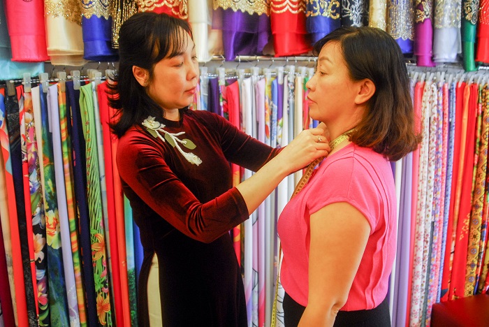 Chị Đinh Thị Lê Dơn (bên trái) đang lấy số đo may áo dài cho khách.