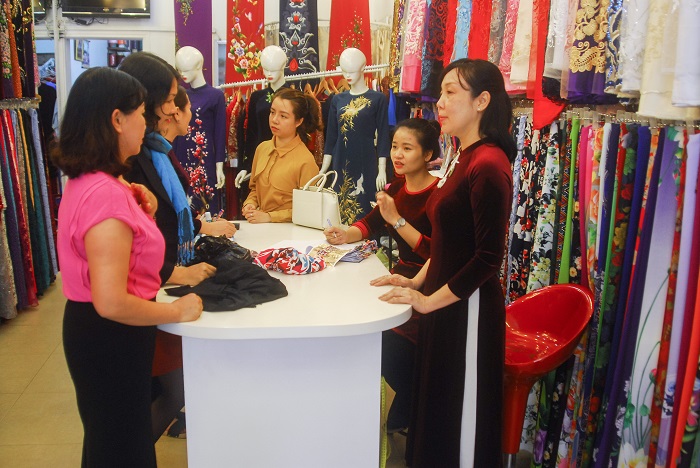 Chị Lê Dơn tư vấn giúp khách chọn mua áo dài tại cửa hàng.