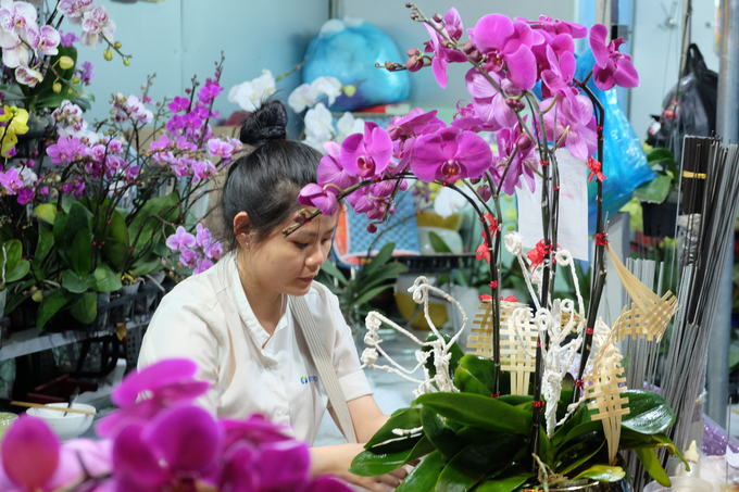 Cô nhân viên của một shop hoa lan tại chợ cho biết đã phải cắm hoa xuyên đêm để kịp giao hàng cho khách vào buổi sáng.