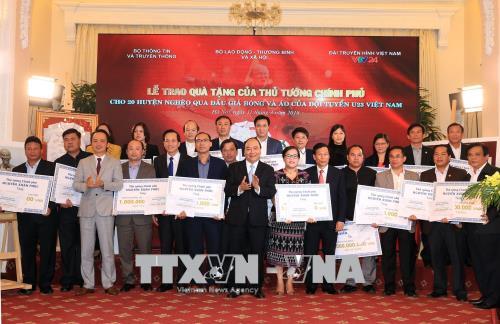 Thủ tướng Nguyễn Xuân Phúc trao tặng tiền số tiền cho 20 huyện nghèo qua đấu giá trái bóng và áo Đội tuyển U23 Việt Nam. Ảnh: Thống Nhất/TTXVN