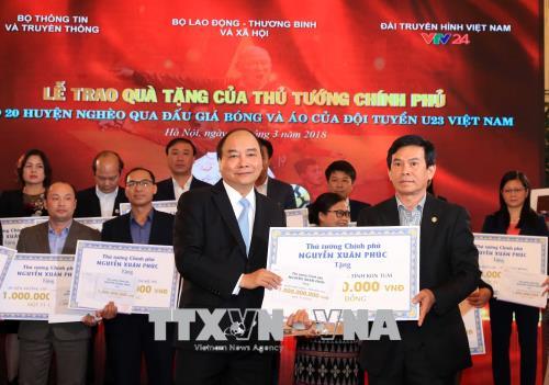  Thủ tướng Nguyễn Xuân Phúc trao tặng tiền số tiền cho 20 huyện nghèo qua đấu giá trái bóng và áo Đội tuyển U23 Việt Nam. Ảnh: Thống Nhất/TTXVN
