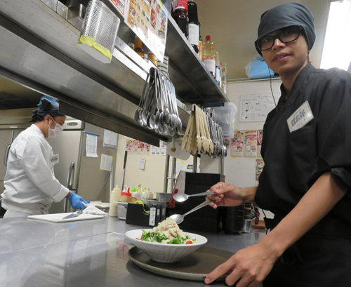 Một lao động người Việt Nam (phải) chuẩn bị món ăn trong bếp của nhà hàng Amataro ở Nagoya, Nhật Bản. Ảnh: Chunichi Shimbun. 