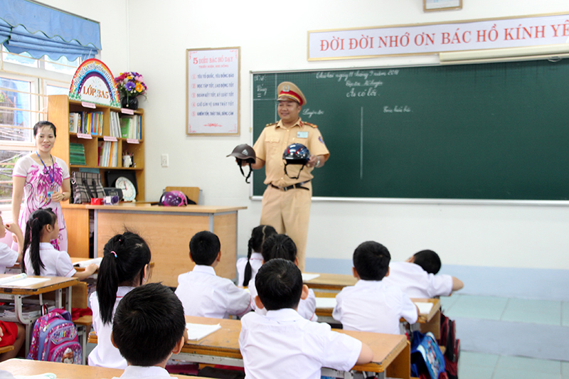 Công an TP Hạ Long hướng dẫn học sinh đội mũ bảo hiểm an toàn, đúng cách tại Trường Tiểu học Quang Trung. Ảnh Lan Anh (dùng lại lần 2)