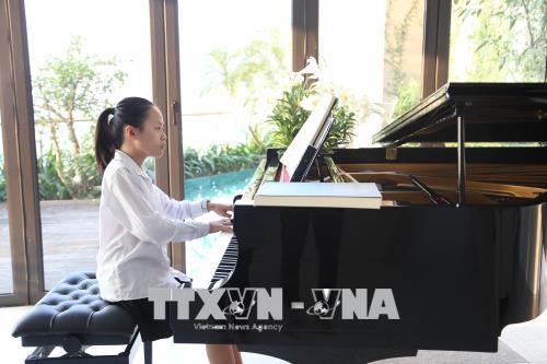 Trần Minh Châu bên cây đàn piano. Ảnh: Nguyễn Văn Cảnh/TTXVN
