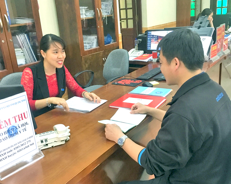Nhân viên BHXH huyện Tiên Yên hướng dẫn người dân tham gia BHYT tại Trung tâm hành chính công huyện Tiên Yên.