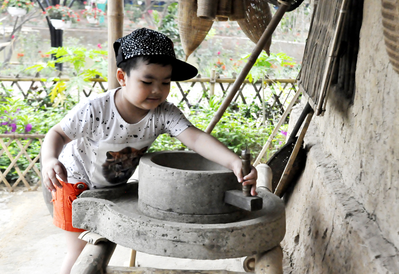 Một du khách nhỏ tuổi thử vận hành chiếc cối xay bột thủ công