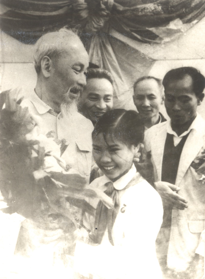 Bác Hồ tươi cười đón nhận bó hoa tươi thắm của các cháu thiếu nhi Uông Bí tặng Người ngày mồng một Tết Ất Tỵ (1965).