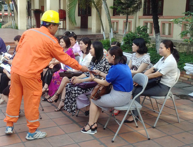 Nhân viên Điện lực Uông Bí phát tờ rơi hướng dẫn sử dụng điện tiết kiệm cho CBNV trường THCS Trần Quốc Toản, TP Uông Bí