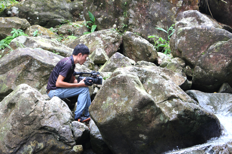 Phóng viên quay phim Quốc Nghị đang tác nghiệp tại thác Bạch Vân, xã Quảng An, huyện Đầm Hà.
